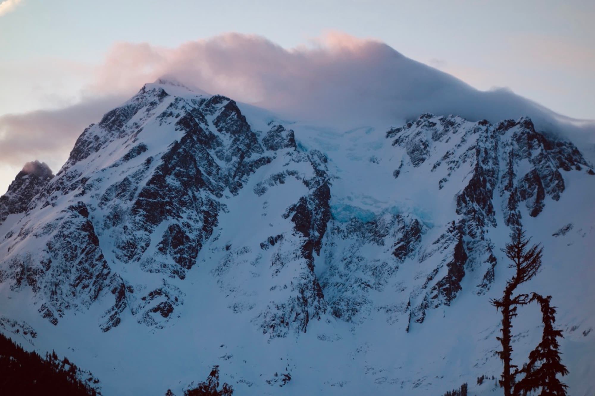 Mount Shuksan's glaciated face at dusk, with cloud spilling over the summit